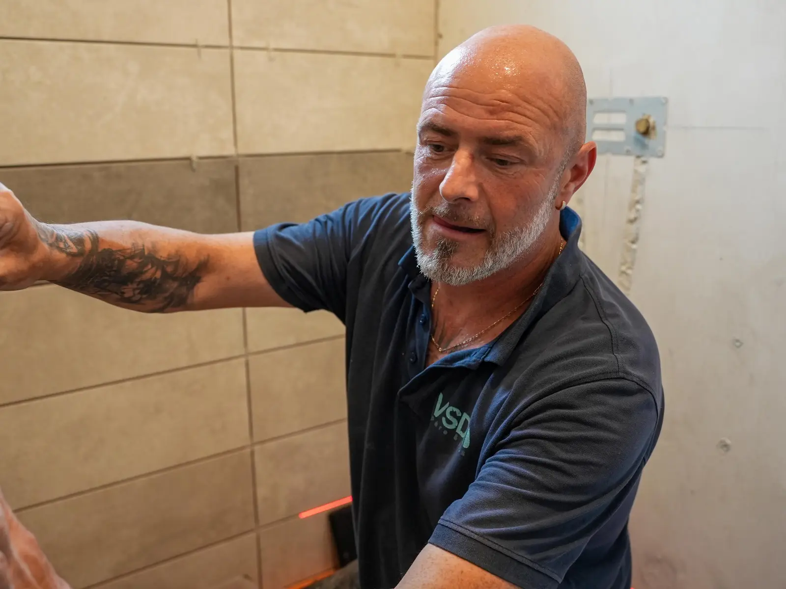 Artisan examinant un mur carrelé lors d’une rénovation de salle de bains